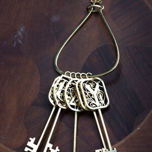 Leierförmiger Schlüsselring aus Messing „Schlüssel und Symbole“